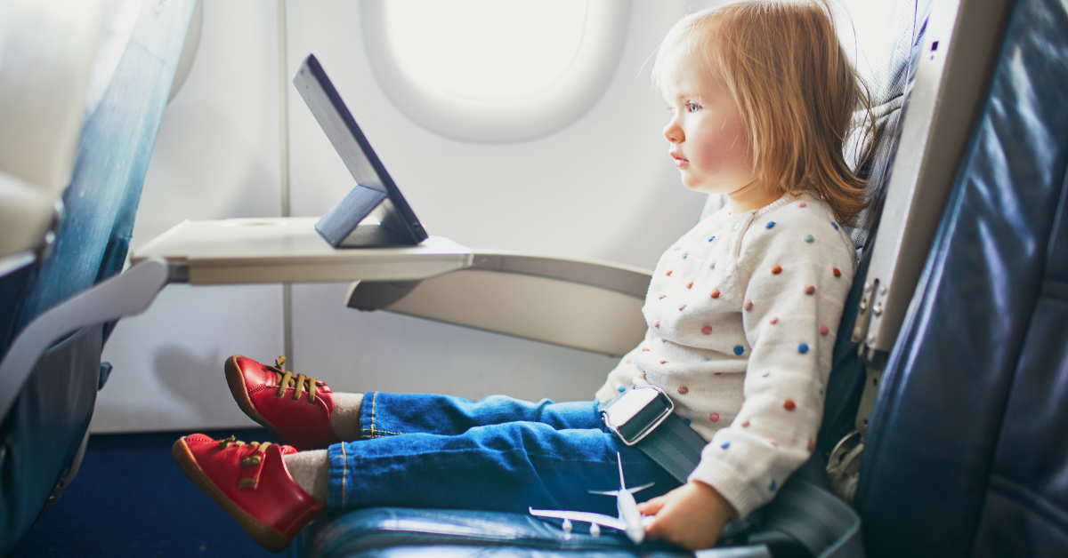 Niño feliz jugando con una tableta en el asiento del avión.