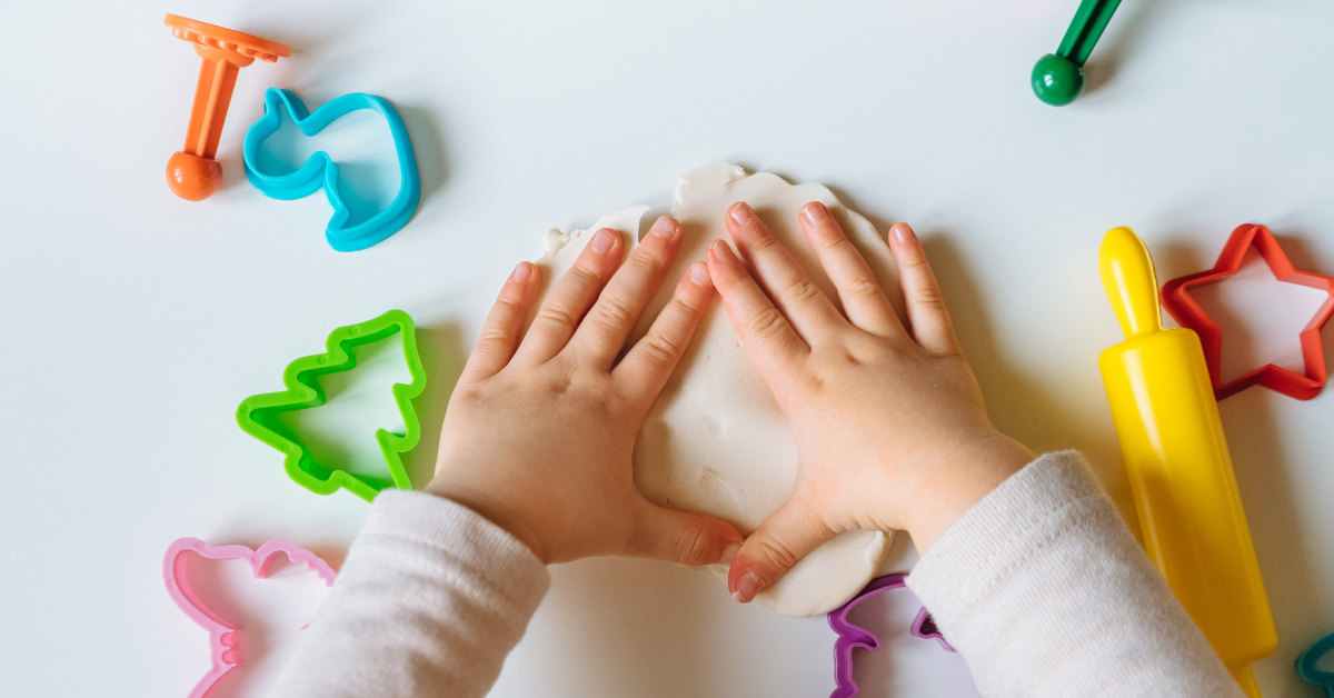 Happy child playing with colorful Play-Doh shapes